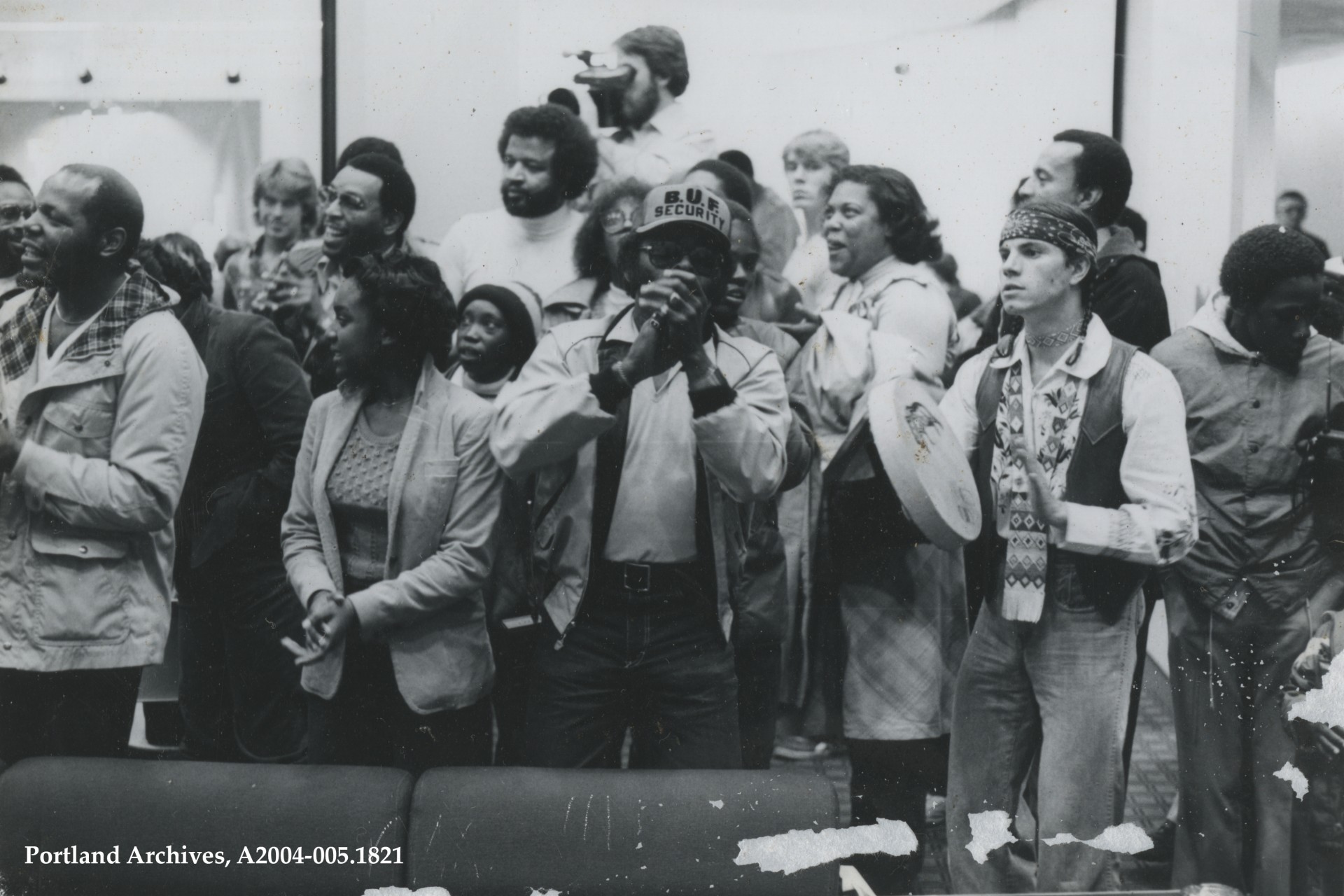 Black and white image of a group of people standing while protesting at a school board meeting in 1982.