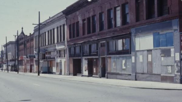 Photograph of a row of commercial properties with boarded up doors and windows along North Williams Avenue and North Russell Street. 1971.