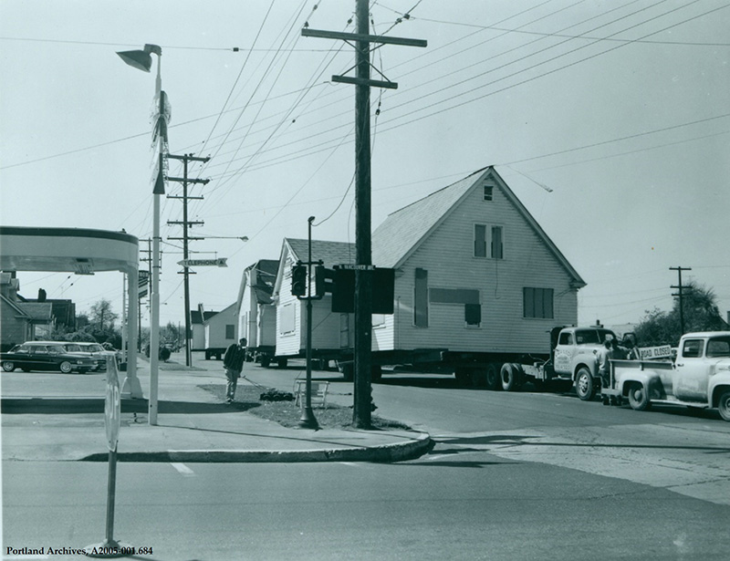 House being moved on a flat bed trailer, pulled by a truck