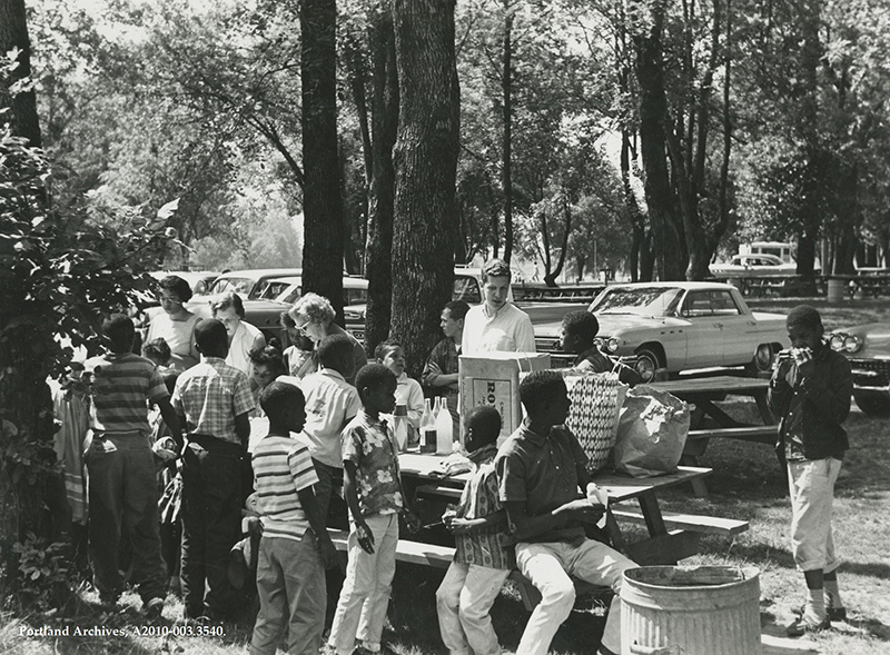 Group of people sitting or standing near a picnic table